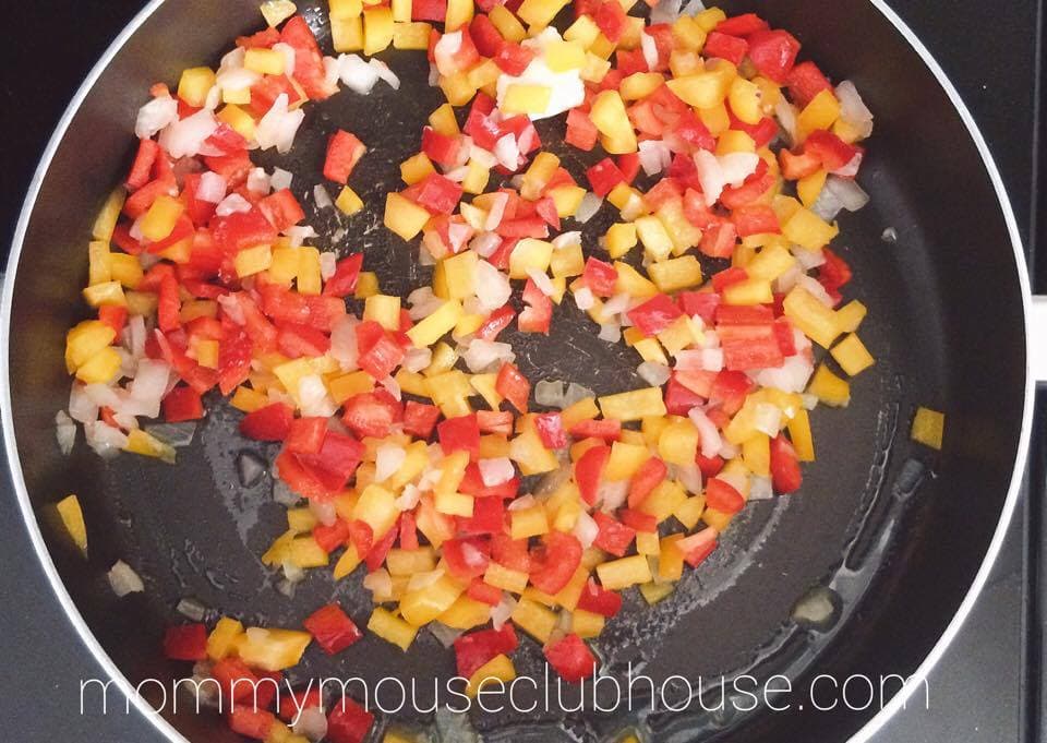 Peppers and onions in a frying pan to make Cheesecake Factory's Louisiana Chicken Pasta 