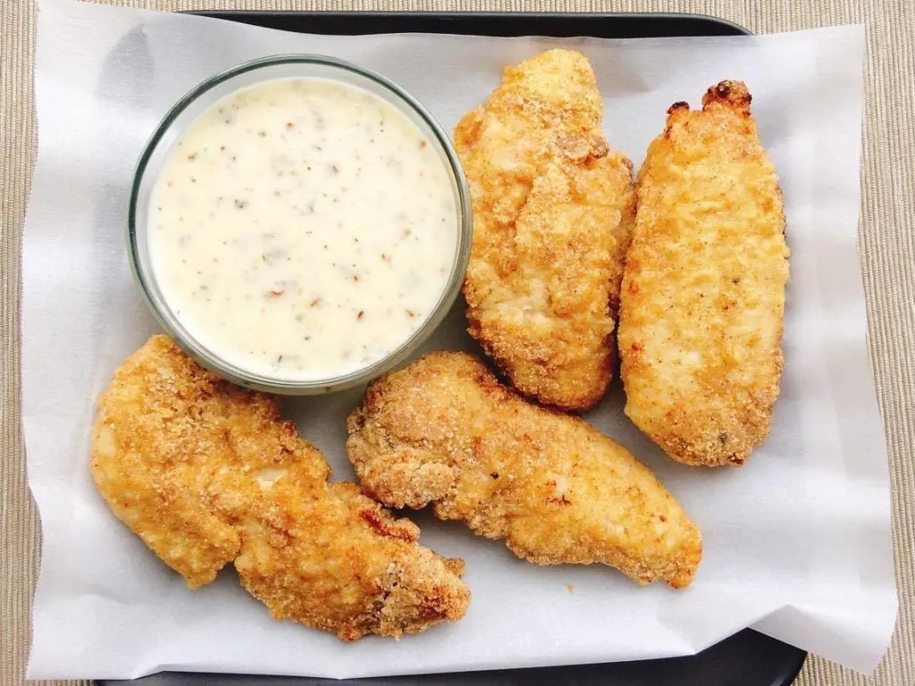 Chicken tenders and a dish of Garlic Parmesan Dipping sauce on a plate.
