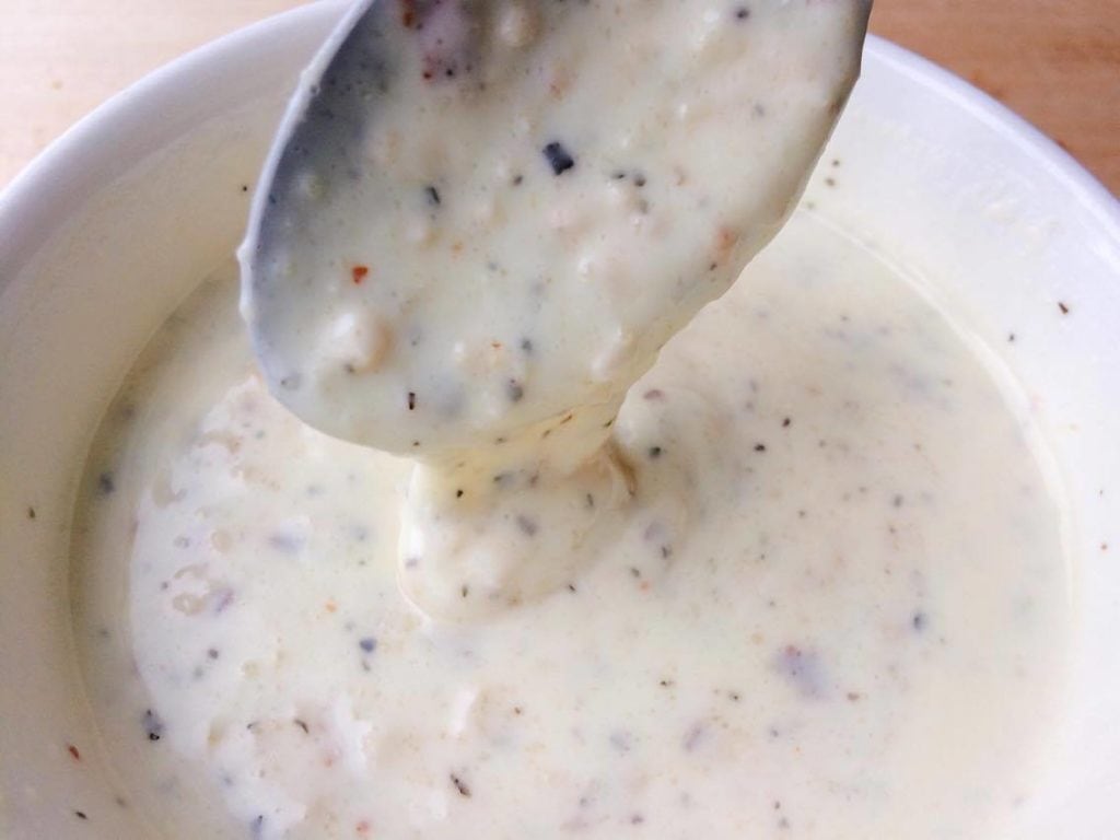 A spoon dipped into a dish of Garlic Parmesan Dipping Sauce for chicken.
