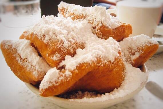 Beignets on a plate with powdered sugar.