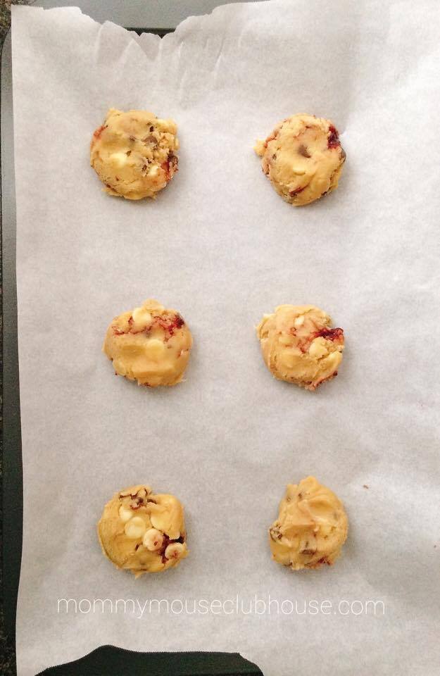 Cookie dough circles on a parchment paper covered baking sheet to make Disneyland's Raspberry White Chocolate Chip Cookies