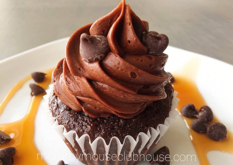 Chocolate Salted Caramel Cupcakes on a plate drizzled with caramel and sprinkled with chocolate chips
