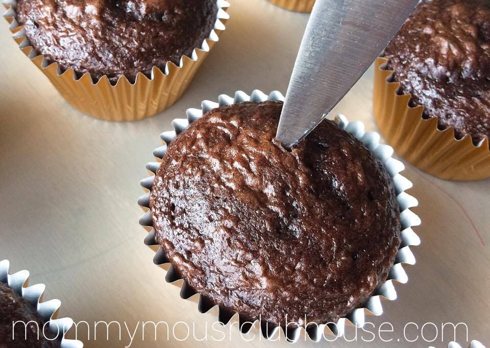 A knife cutting a hole in the center of a cupcake to make Chocolate Salted Caramel Cupcakes
