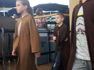 Kids wearing long brown robes are walking out to do Jedi Training at Disneyland