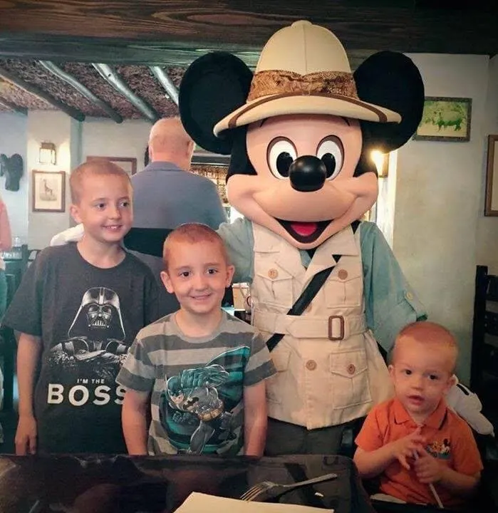 Mickey Mouse and three boys posed at Tusker House, one of The Best Disney World Character Meals