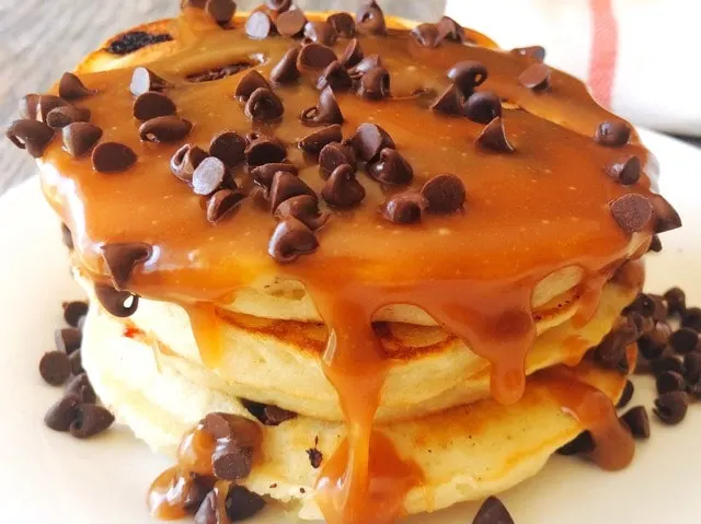 A stack of sweet cream pancakes topped with syrup and chocolate chips