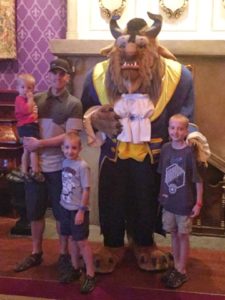 A family posed with The Beast at Be Our Guest Restaurant