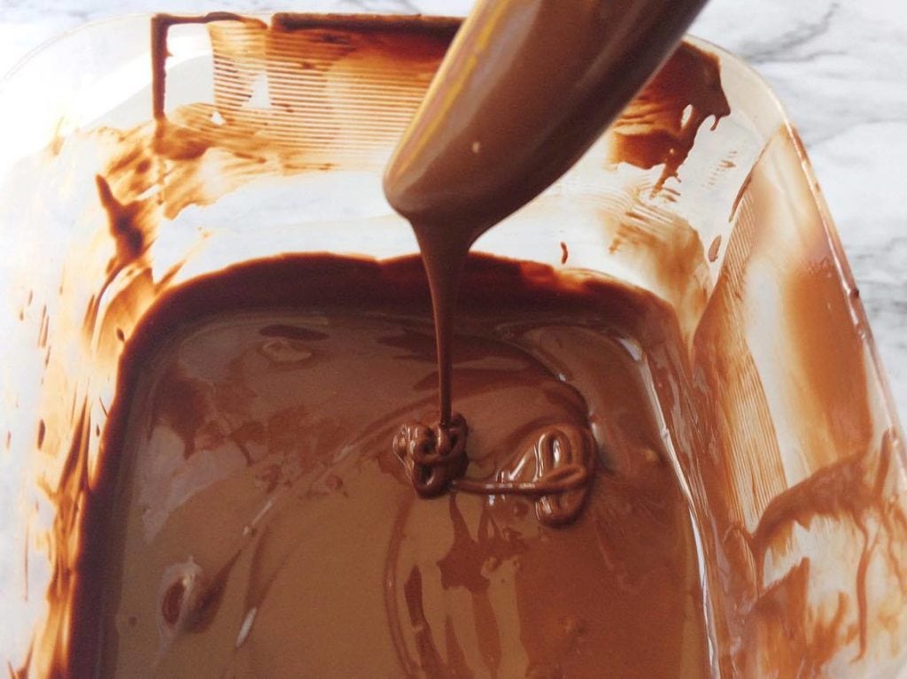 A spoon drizzling homemade magic shell to make Homemade Hand Dipped Ice Cream Bars