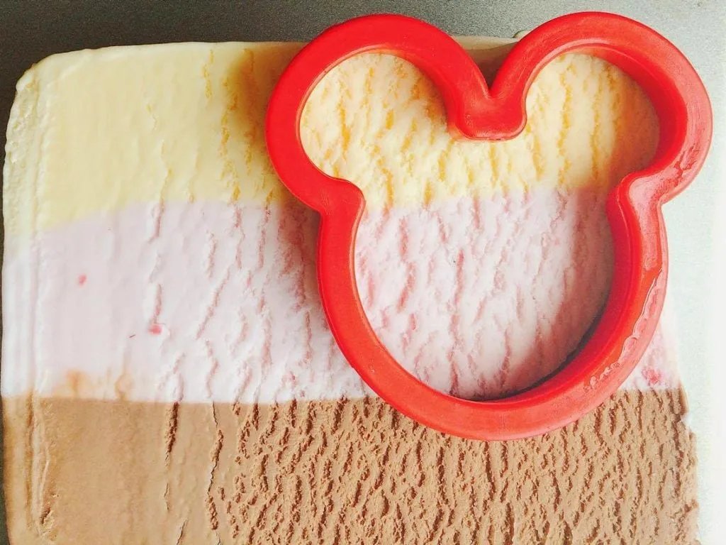 Step 3 A Mickey Mouse shaped Cookie Cutter cutting ice cream to make Homemade Hand Dipped Ice Cream Bars