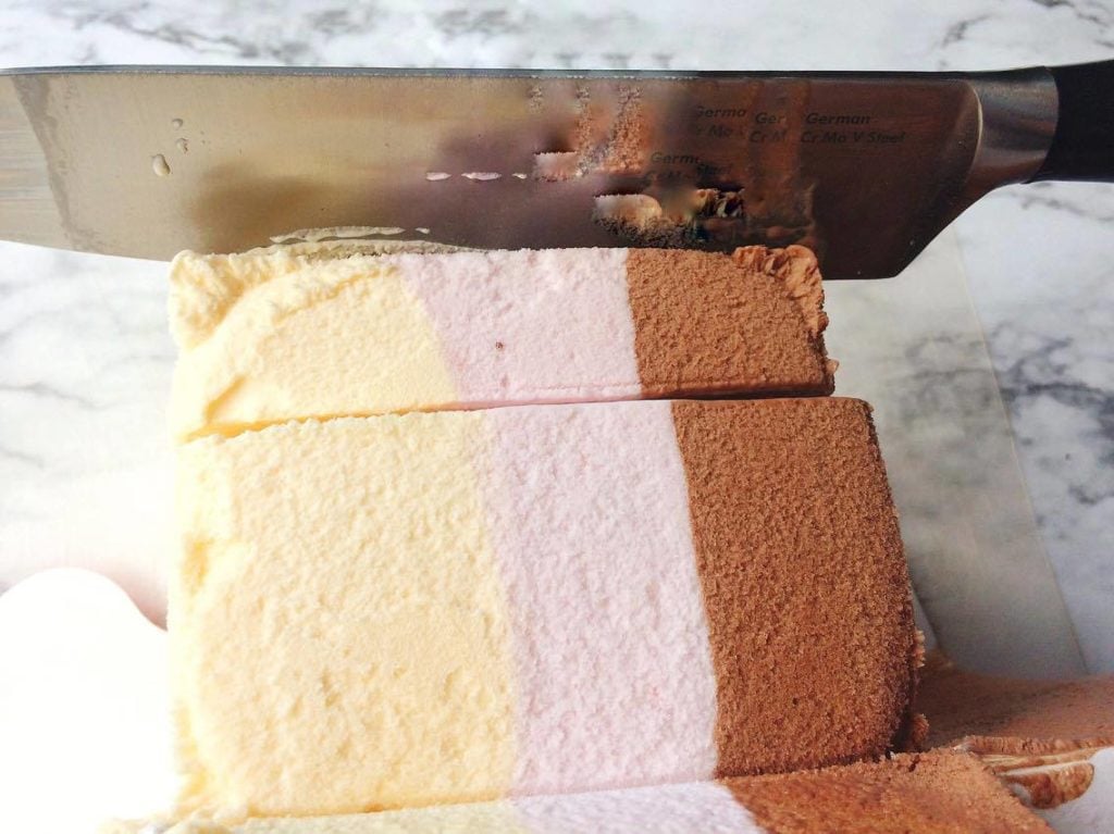 Step 2 A block of Neopolitan Ice Cream being cut with a large knife.