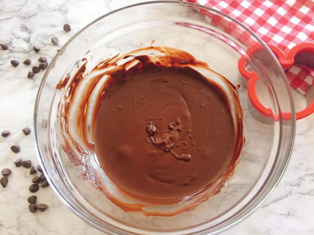 A bowl of melted chocolate with chocolate chips scattered around to make Homemade Hand Dipped Ice Cream Bars