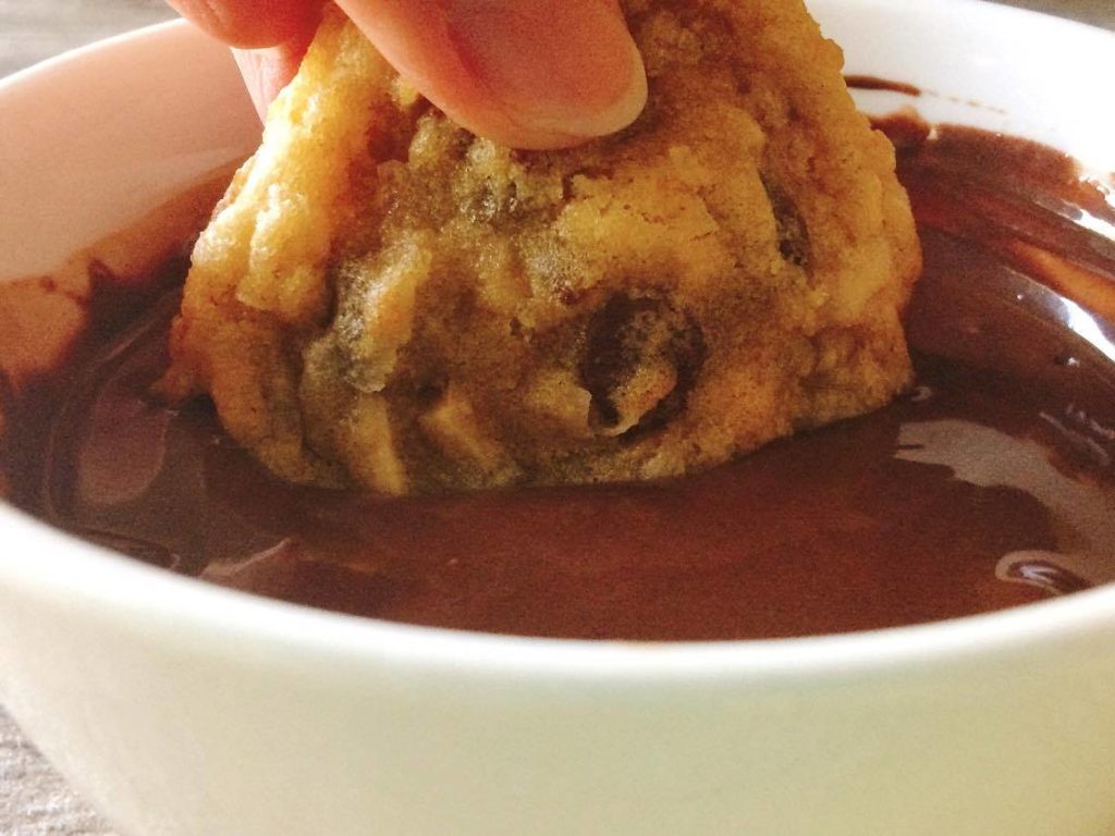 Almond Joy Crunch Cookies being dipped in melted chocolate