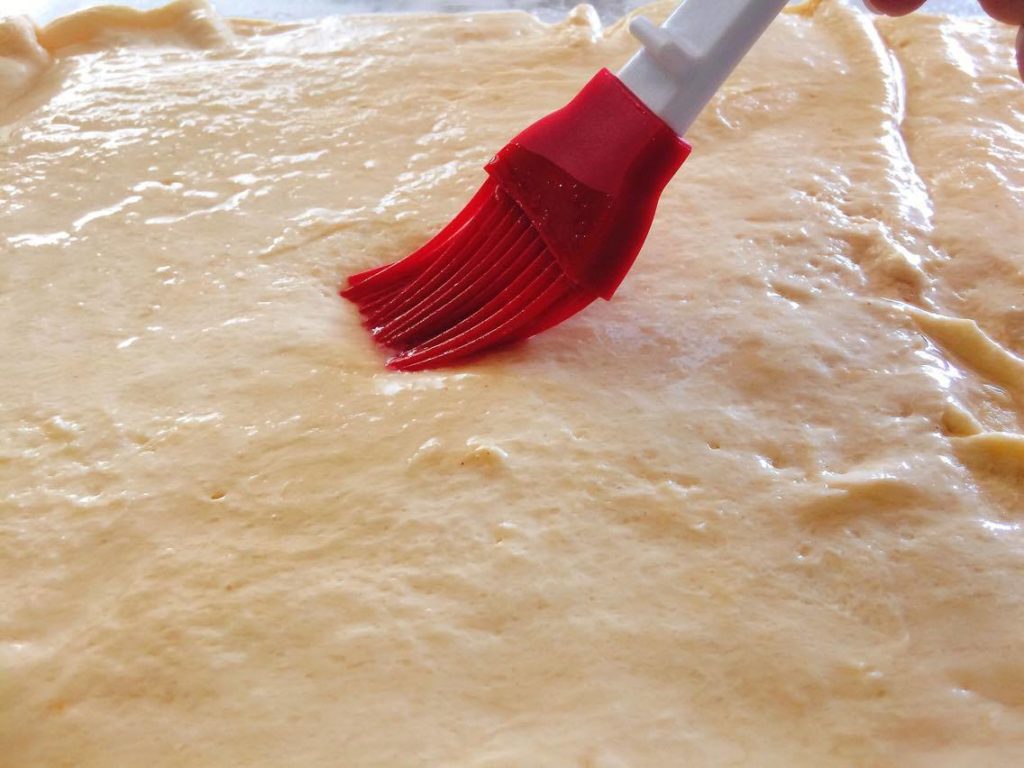Butter being brushed on the crust of Easy Pumpkin Cheesecake Danish