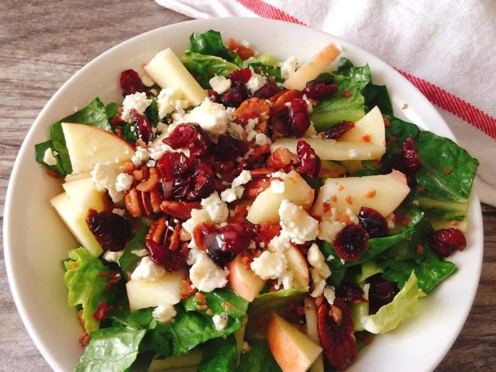 Honeycrisp Harvest Salad in a white bowl with a wood background and a kitchen towel
