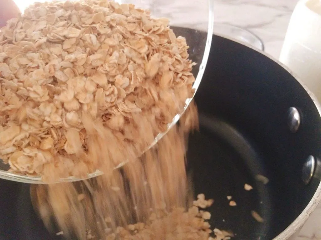 Oats being poured into a pan for oatmeal.