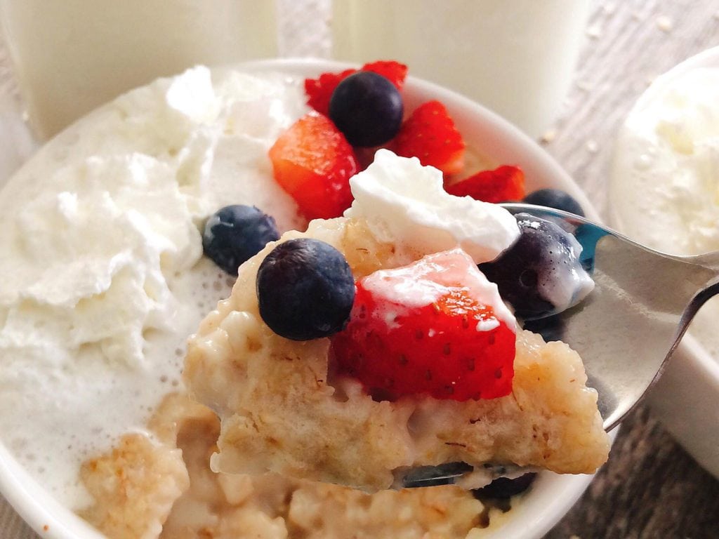 A spoonful of oatmeal with berries and whipped cream.