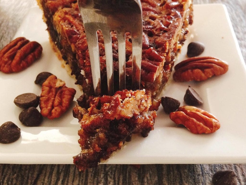 A fork taking a bite out of Dark Chocolate Pecan Pie