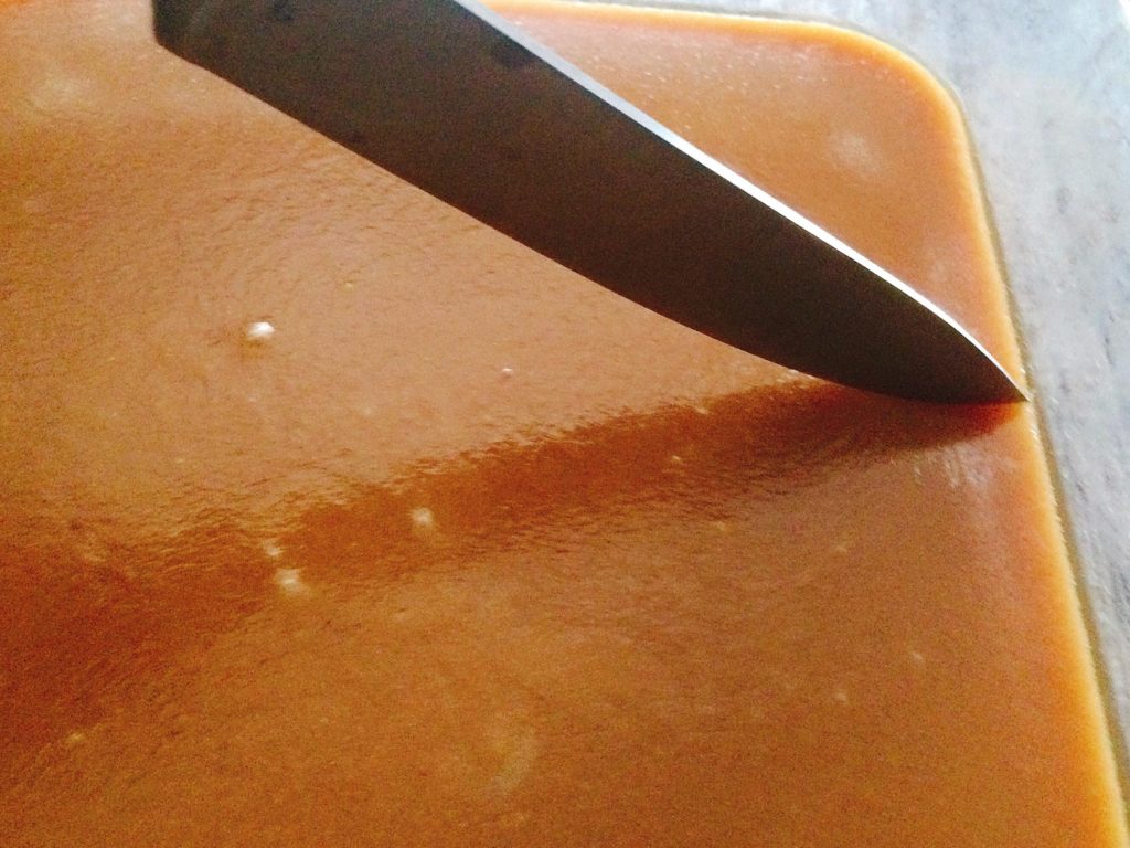 A knife cutting through a dish of Easy Microwave Soft Caramels