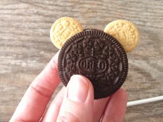 A hand holding an Oreo with two small Oreo mouse ears.