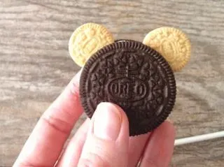A hand holding an Oreo with two small Oreo mouse ears.