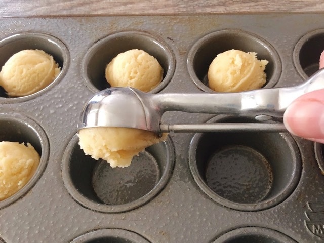 Cookie scoop with Easter sugar cookie dough over a mini muffin pan