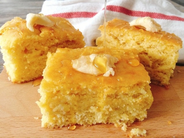 Honey drizzled on three pieces of cornbread topped with butter.