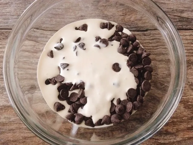 Heavy cream and chocolate chips in a bowl.