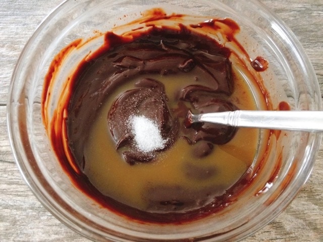 Melted chocolate ganache, caramel, and salt in a bowl.