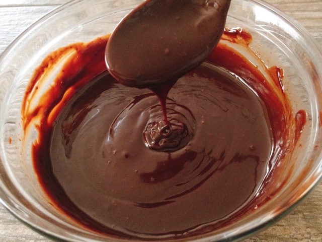 A spoon with salted caramel ganache over a bowl.