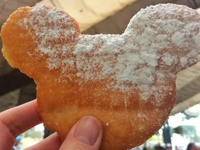 A hand holding up a Mickey Beignet at Disneyland