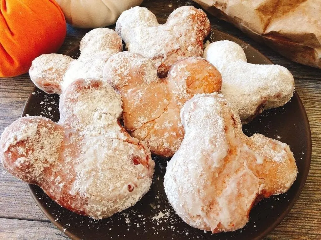 A plate full of Mickey Mouse shaped beignets, covered in powdered sugar.
