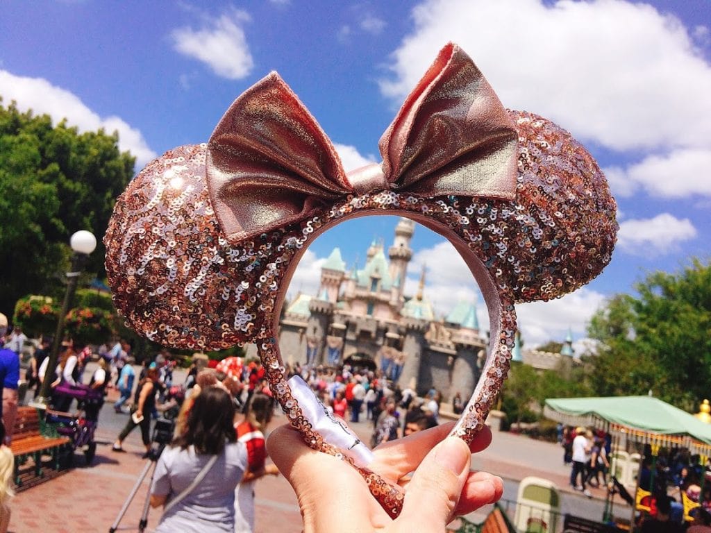 A pair of Rose Gold Minnie Mouse Ears in front of Sleeping Beauty's Castle at Disneyland
