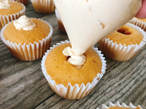 Butterscotch whipped cream being piped into the middle of a butter beer cupcake.