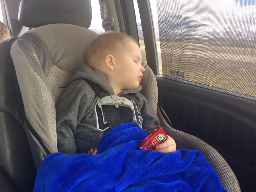 A toddler asleep in a car seat