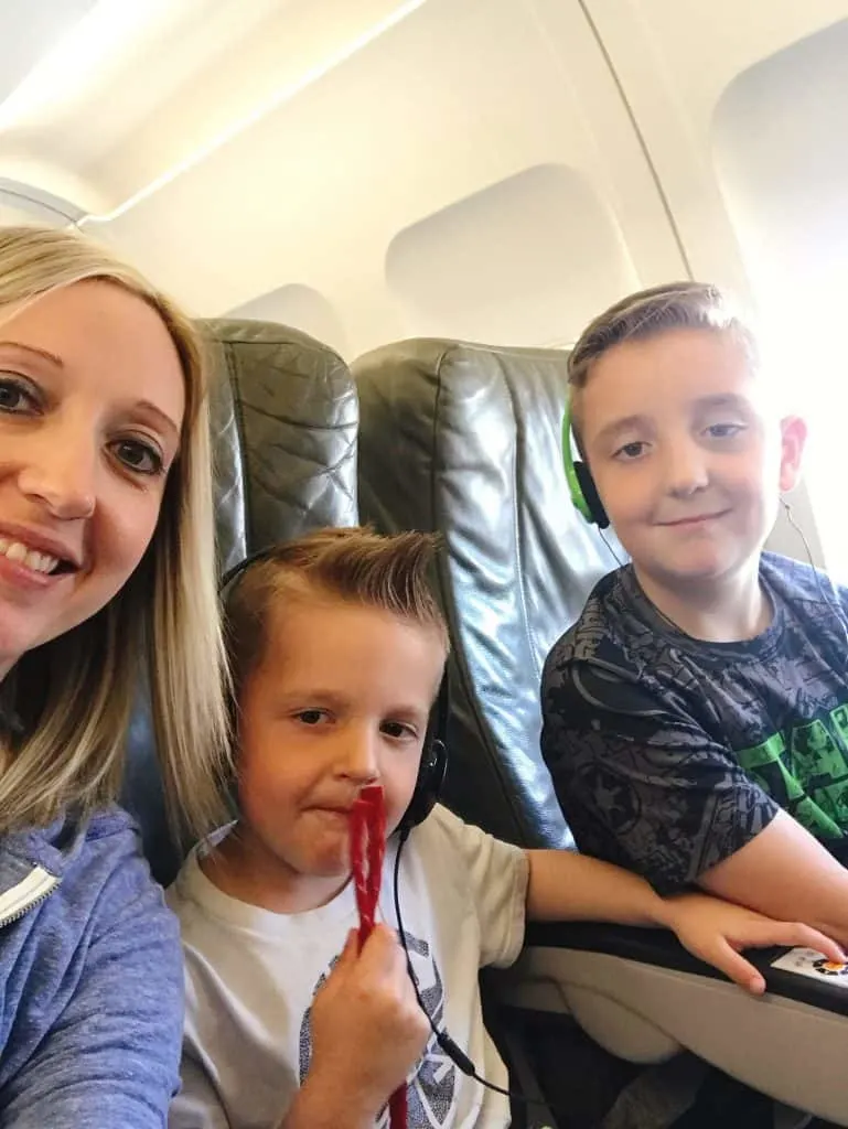 A woman and two kids sitting inside an airplane.