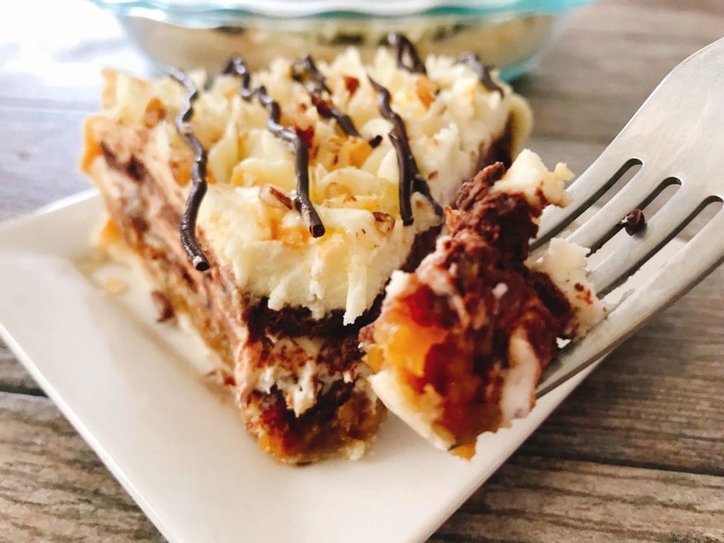 A fork with a bite over a slice of Caramel Pecan Silk Pie.