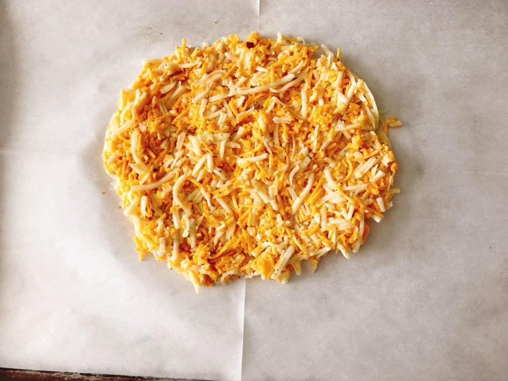 Shredded cheese spread on a baking sheet to make crust for Keto Pizza.
