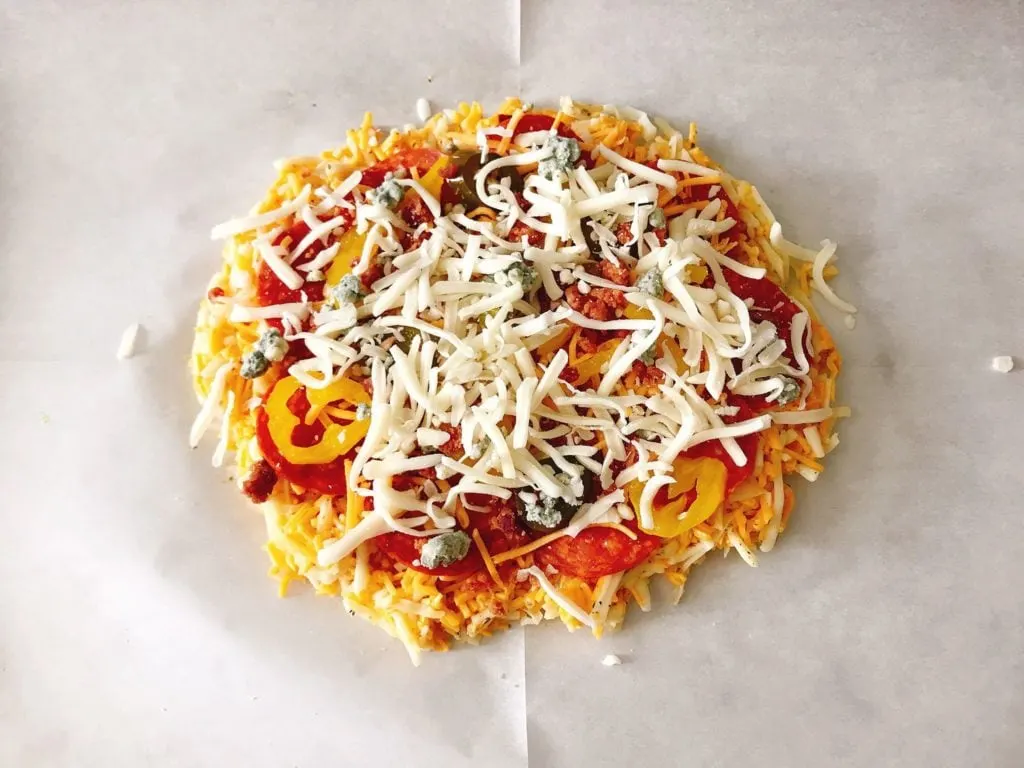 Pepperoni, peppers and other toppings topped with shredded mozzarella on Keto Pizza.
