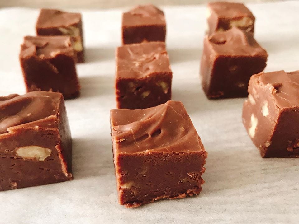 Squares of easy homemade fudge recipe lined up on parchment paper.