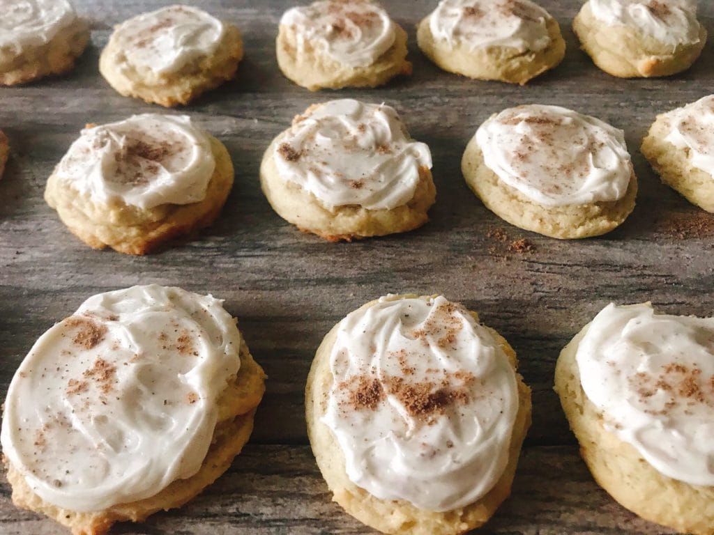 Freshly Frosted Eggnog Christmas Cookies sprinkled with nutmeg lined up.