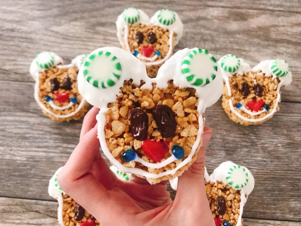 A hand holding up a decorated Mickey Mouse Gingerbread Rice Krispie Treat.