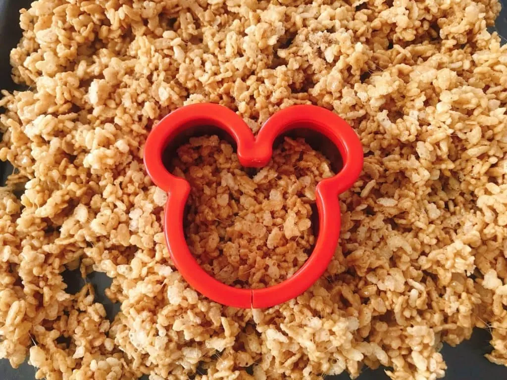 A pan of warm Gingerbread Rice Krispie Treats with a Mickey Mouse cookie cutter.