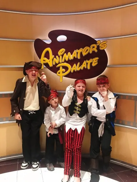 Kids dressed up as pirates in front of the Animator's Palate sign on a Disney Cruise.