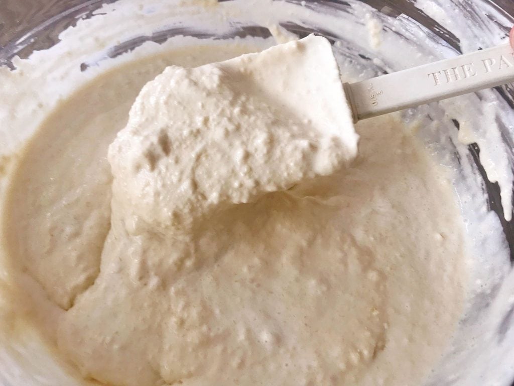 A spoon holding up a spoonful of sweet cream waffle batter.