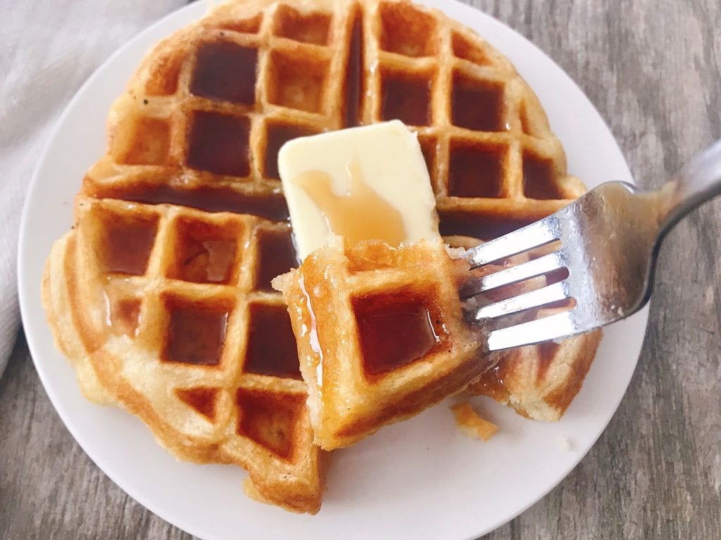 A fork holding up a piece of Sweet Cream Waffles.