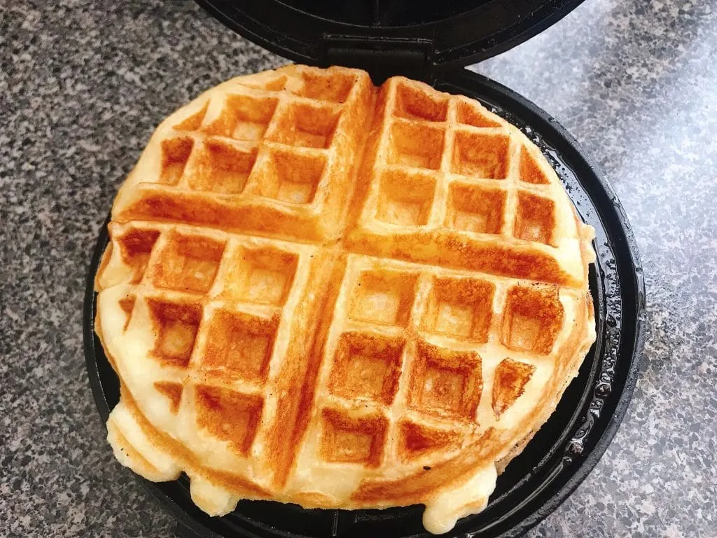 A golden brown sweet cream waffle on a waffle iron.