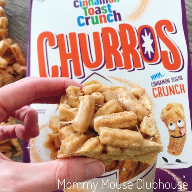 A Churro Cereal Treat being held over a box of Cinnamon Toast Crunch Churros.