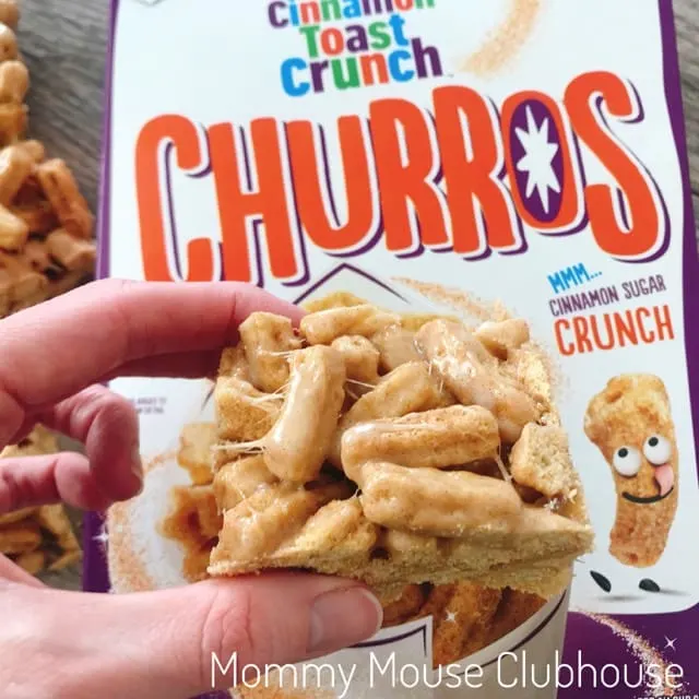 A Churro Cereal Treat being held over a box of Cinnamon Toast Crunch Churros.