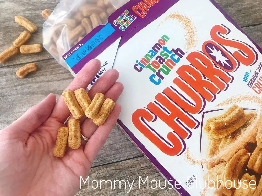 A handful of Cinnamon Toast Crunch Churros over a box of them.
