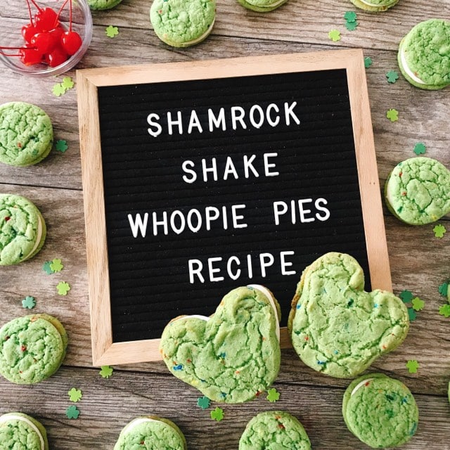 A letter board with the words "Shamrock Shake Whoopie Pies" with green whoopie pies and a bowl of cherries.